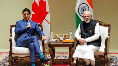 Justin Trudeau și Narendra Modi pe scaune la masă, cu steagurile Canadei și Indiei în spate