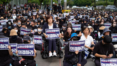 oameni îmbrăcați în negru cu pancarte în mâini la un protest al profesorilor de la Seul