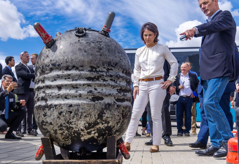 14 July 2022, Mecklenburg-Western Pomerania, Rostock: Annalena Baerbock (Bndnis 90/Die Grnen), Foreign Minister, stands behind a water mine (sea mine) from the First World War recovered in the North Sea during her visit to the Fraunhofer Institute for Com