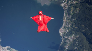 Wingsuit skydiver pilot flying over lake, Locarno, Tessin, Switzerland