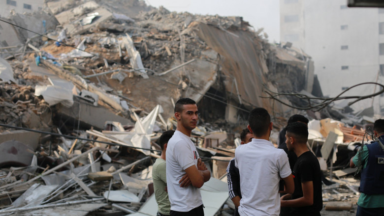 Palestinians inspect the ruins of Watan Tower destroyed in Israeli airstrikes