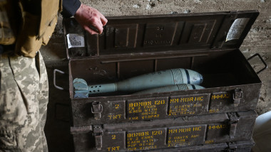 Un militar ucrainean deschide o cutie cu proiectile de mortier