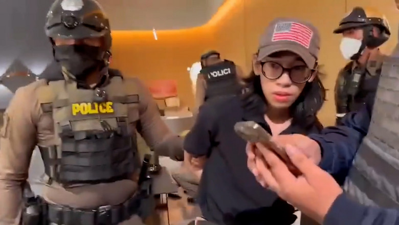 Copil cu ochelari și șapcă ținut de mâini de un polițist în uniformă specială