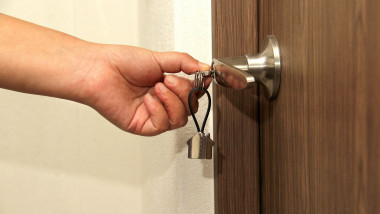 O mână deschide ușa cu cheia