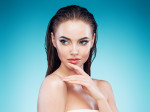 Beautiful girl with wet hair posing against blue background