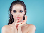 Beautiful girl with wet hair posing against blue background