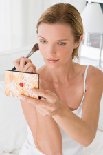 A young woman applying blusher