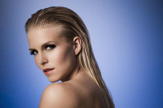 Sexy model with wet hair posing against a blue background