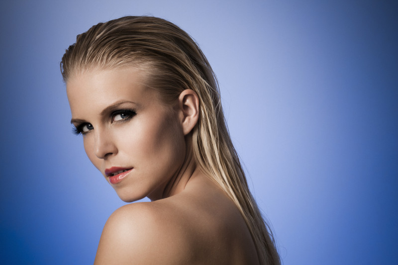 Sexy model with wet hair posing against a blue background