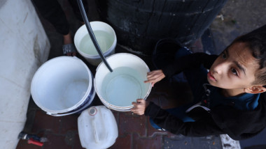 A Palestinian youth fills a bucket with water at the Rafah refugee camp