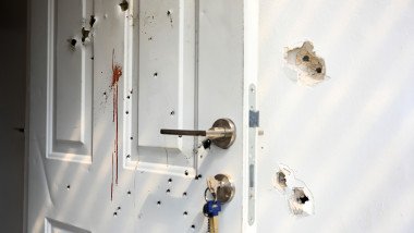ușă albă lovită de gloanțe și pătată de sânge în kibbutzul Kfar Azza din Israel