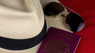 Straw hat with passport and sungtlasses on a red background