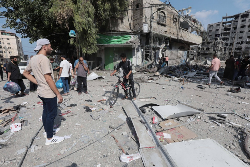 Palestinians walk through debris and destruction littering a street in al-Karama district in Gaza City