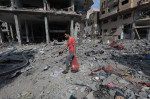 Palestinians walk through debris and destruction littering a street in al-Karama district in Gaza City