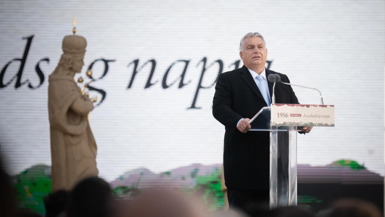 v orban la pupitru cu microfon, in spate o statuie de sfant