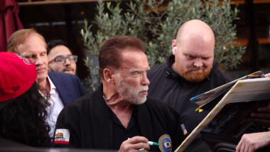 Arnold Schwarzenegger din profil cu un pix in mana