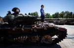 Kyiv, Ukraine. 28th July, 2023. A boy stands on a destroyed Russian tank on display in central Kyiv. Credit: SOPA Images Limited/Alamy Live News