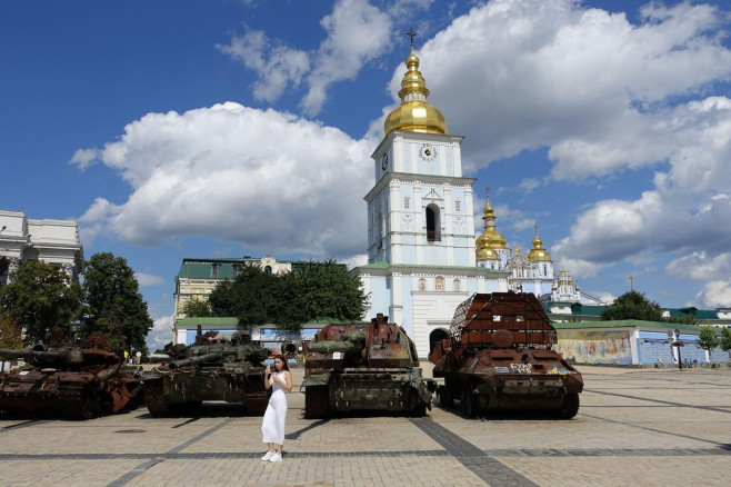 A girl is making a selfie in front of destroyed Russian army armored vehicles displayed on a square in central Kyiv, Ukraine