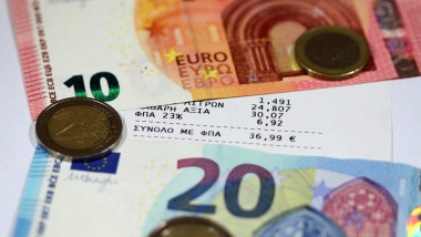 bancnote si monede euro in jurul unui bon fiscal din grecia