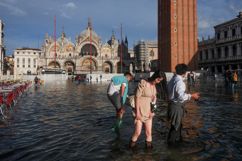 People Wade Through Water In A Flooded St. Mark's Square During Seasonal High Water In Venice