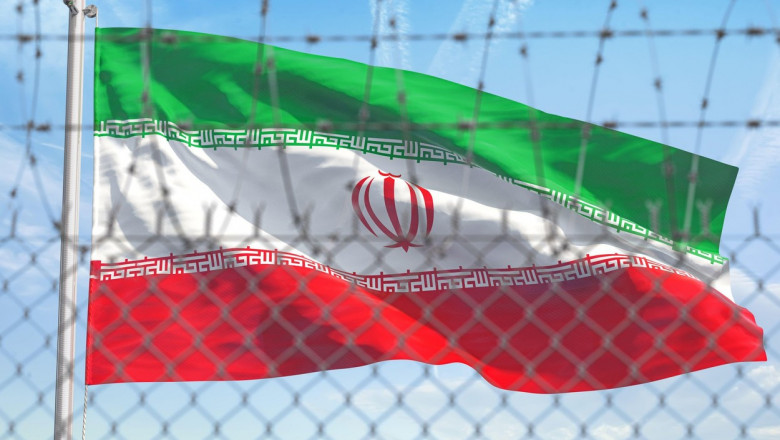 Flag of Iran behind barbed wire fence. Concept of sanctions, embargo, dictatorship, discrimination and violation of human rights and freedom in Iran.