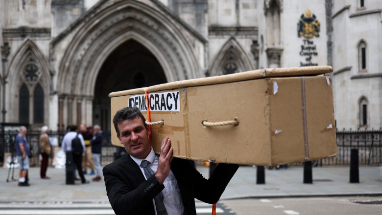 A demonstrator holds a mock coffin reading "Democracy" on the side while taking part in a protest