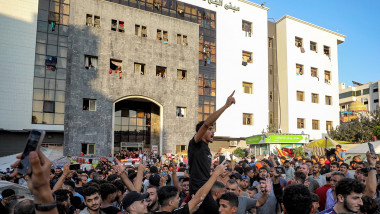 People congregating chant slogans and react outside Al-Shifa hopsital in Gaza City