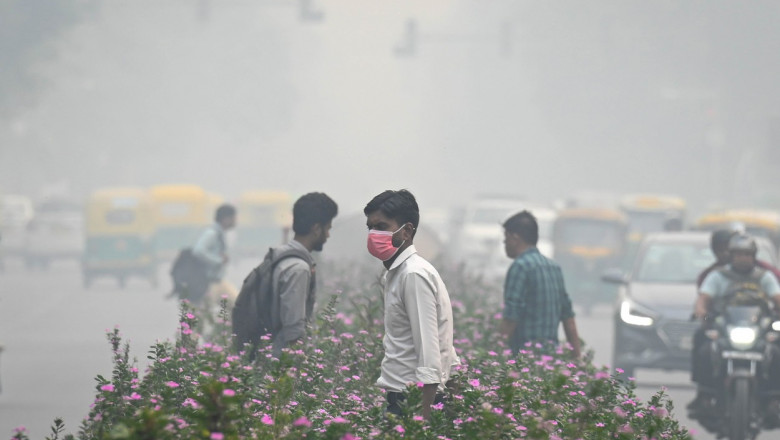 oameni cu masti care se plimba pe strada in new delhi