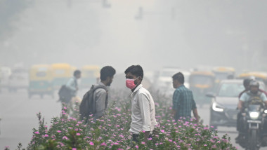 oameni cu masti care se plimba pe strada in new delhi