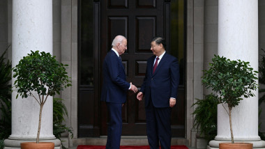 Joe Biden dă mâna cu Xi Jinping pe un covor roșu la intrarea într-o clădire istorică din San Francisco