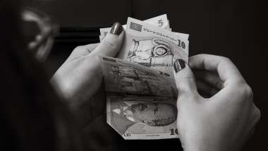 poza alb negru cu mainile unei femeie care numara bani lei