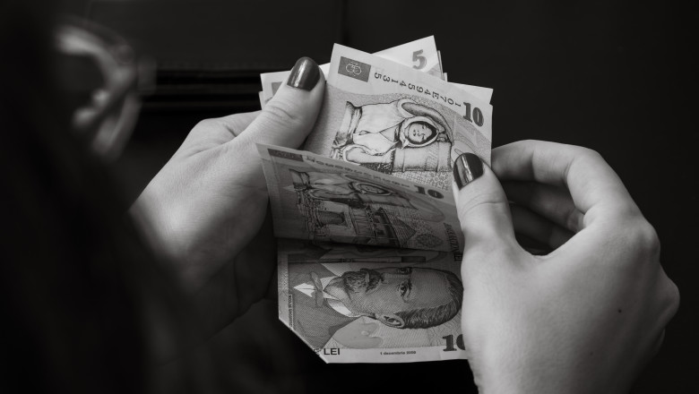 poza alb negru cu mainile unei femeie care numara bani lei