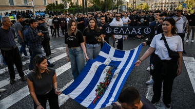 oameni care țin steagul greciei și mărșăluiesc