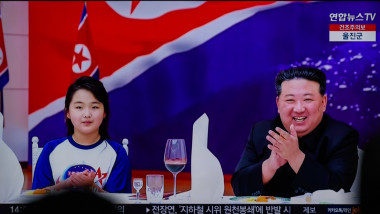 Kim și fiica lui cu un steag nord-coreean în spate