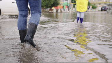 oameni cu cizme pe o strada inundata
