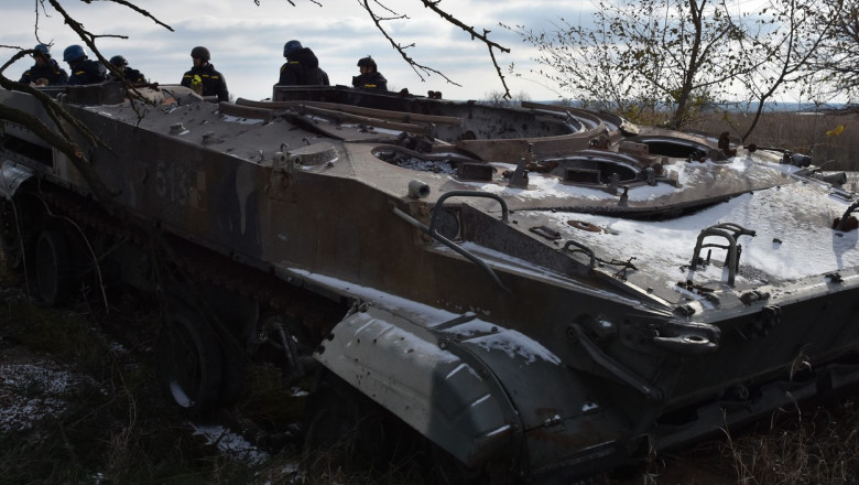 Militari ucraineni lângă un blindat rusesc distrus.