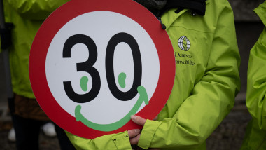 An activist holds a sign for a speed limit of 30 km/h and a smiley in her hand