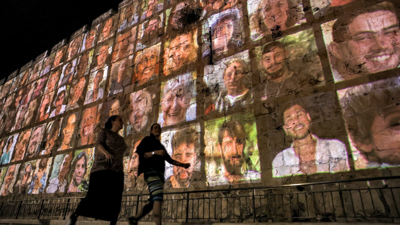 Women walk outside the walls of the old city of Jerusalem, on which are projected pictures of the hostages abducted by Palestinian militants on the October 7 attack