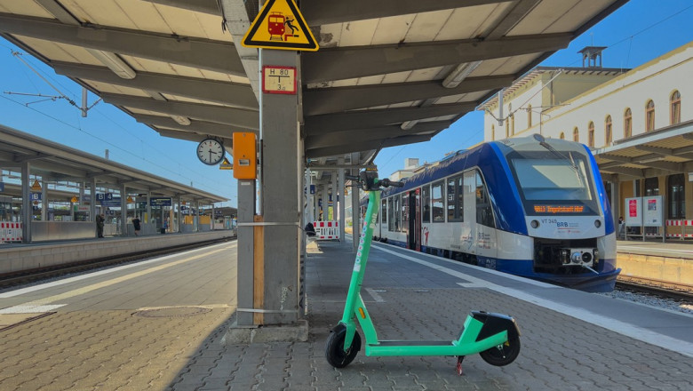 trotineta electrica pe peronul unei gari, langa un tren