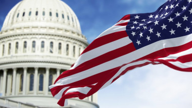 Flag of the United States waving with the American Capitol blurred in the background