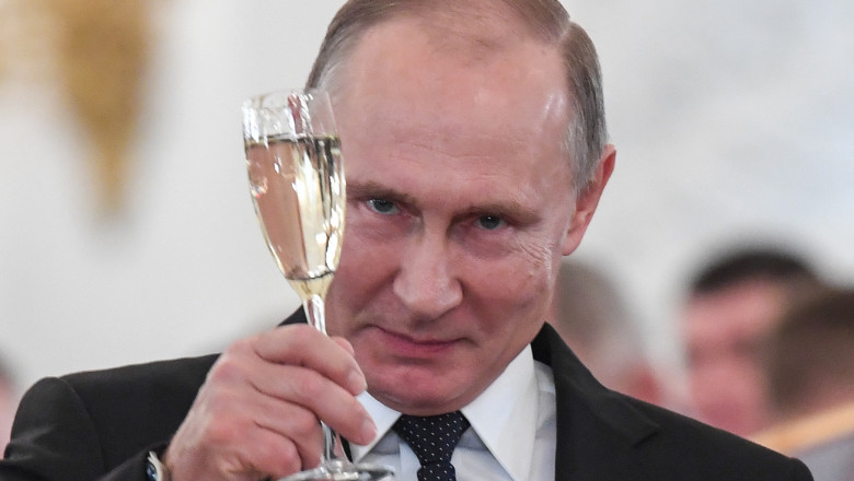 Putin privește spre cameră în timp ce toastează cu un pahar de șampanie