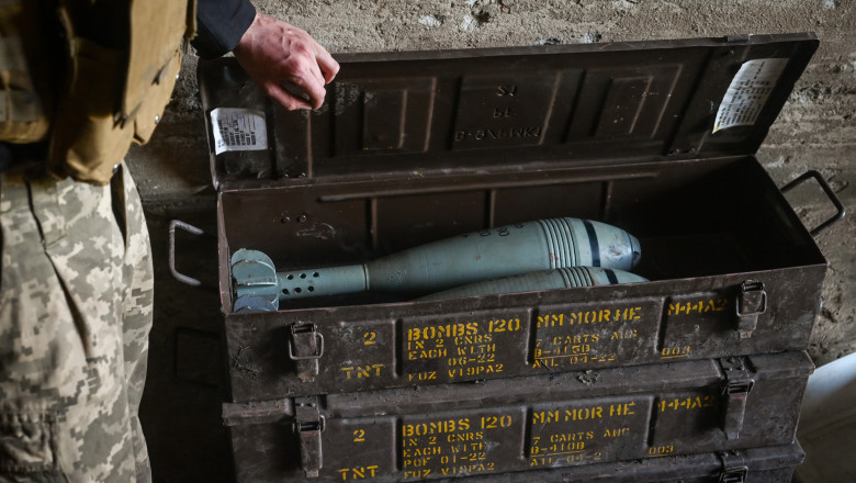 Un militar ucrainean deschide o ladă în care se află proiectile de mortier fabricate în SUA