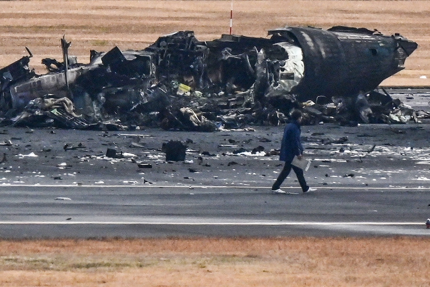 Imagini de pe aeroportul din Tokyo, cu epava înnegrită a avionului distrus ieri de flăcări. Pasagerii au povestit cum s-au salvat