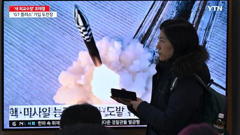 People watch a television screen showing a news broadcast with file footage of a North Korean missile test