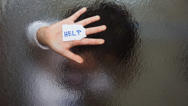 mana unui copil lipita de un geam cu un mesaj help în palmă