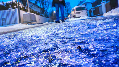 Eisregen morgens um 7:45 Uhr in München, Fußgänger geht vorsichtig auf der extrem glatten Straße, Januar 2024 Deutschlan