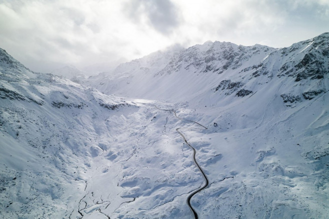 Snow covered peaks of mountains during winter on a sunny day with clouds in Fluela Pass, Davos, Switzerland.