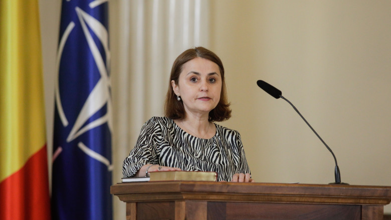 ministra de Externe Luminița Odobescu la pupitru cu steagul NATO în spate