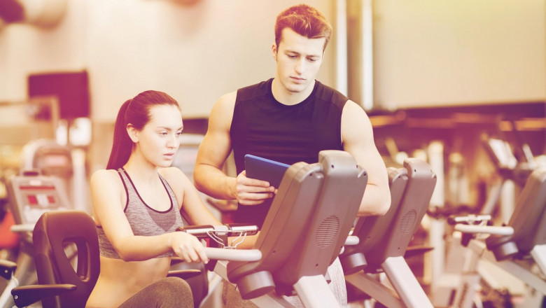 woman with trainer on exercise bike in gym
