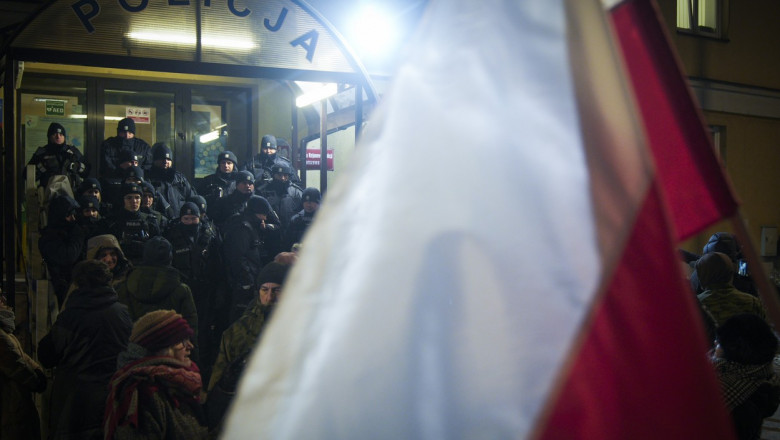 Steag polonez fluturat dintr-o mulțime aflată în fața unei secții de poliție